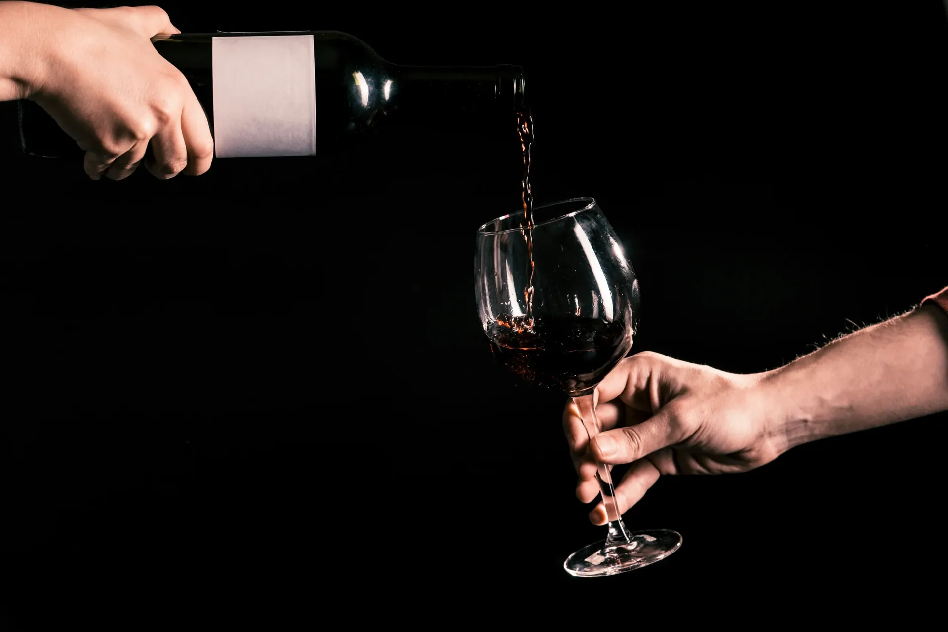 Rotwein wird in ein Glas eingeschenkt