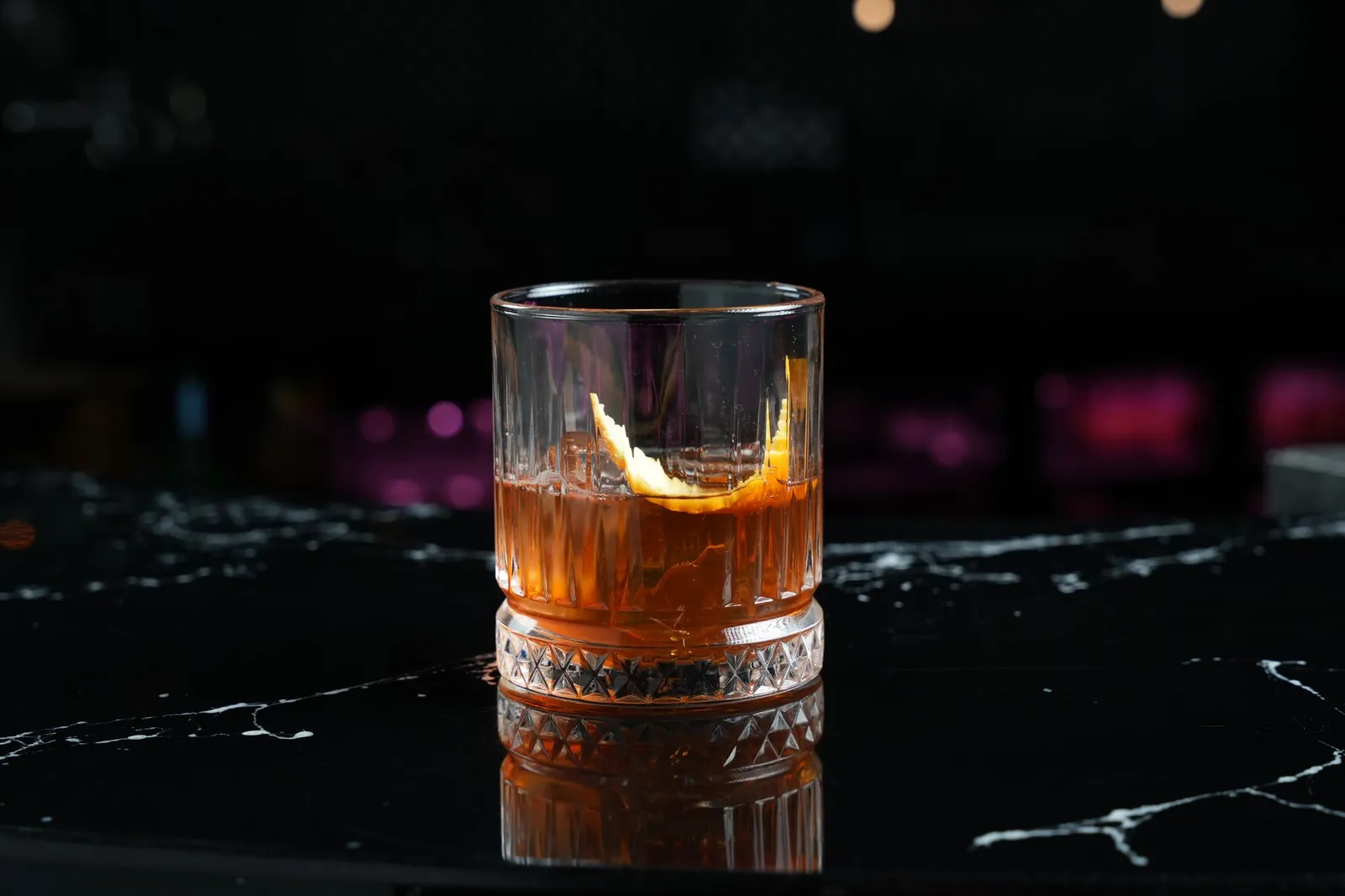 Old Fashioned mit Orangenzeste auf schwarzem Marmortresen